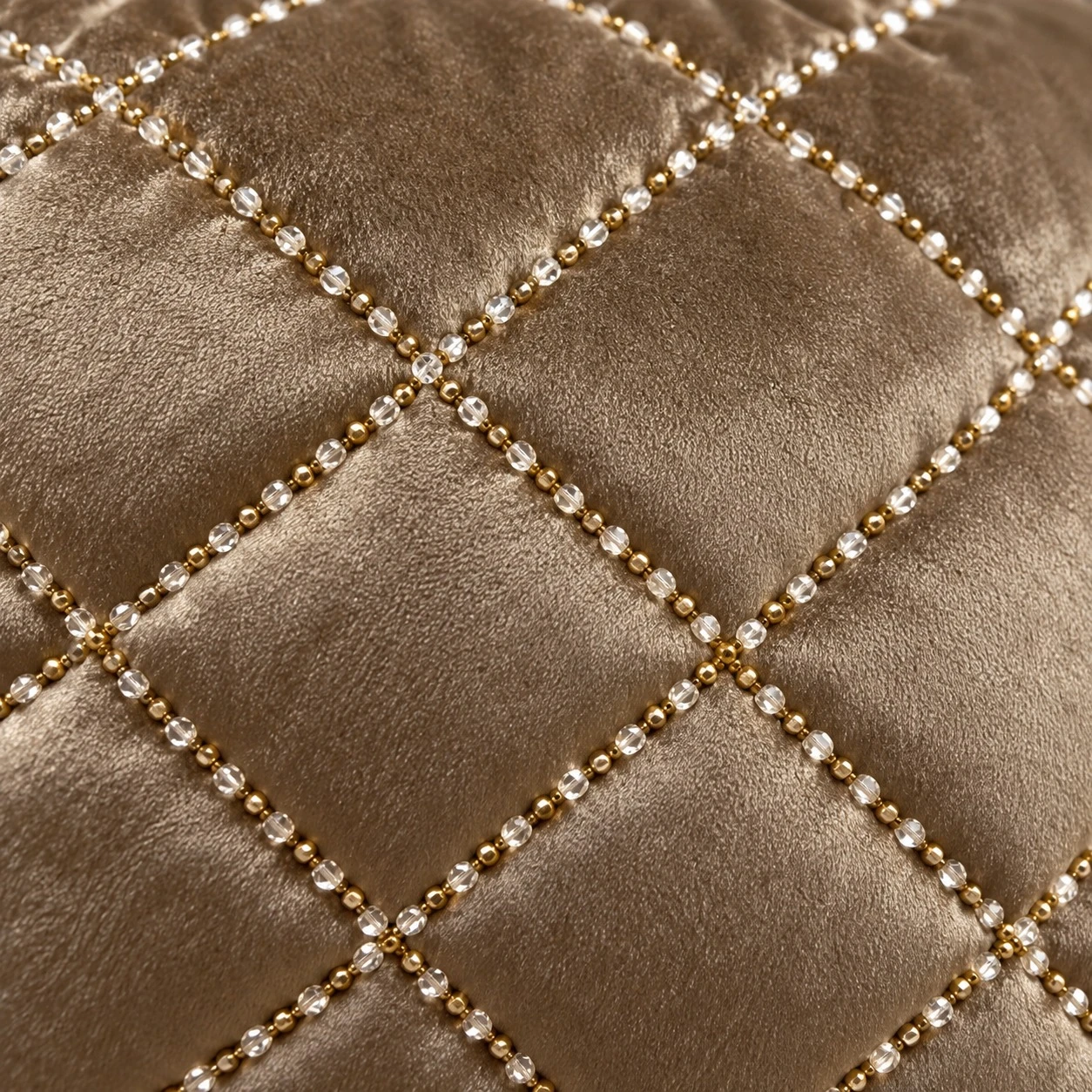 Close-up of taupe velvet with diamond quilting lines of gold and clear beads on the cushion cover